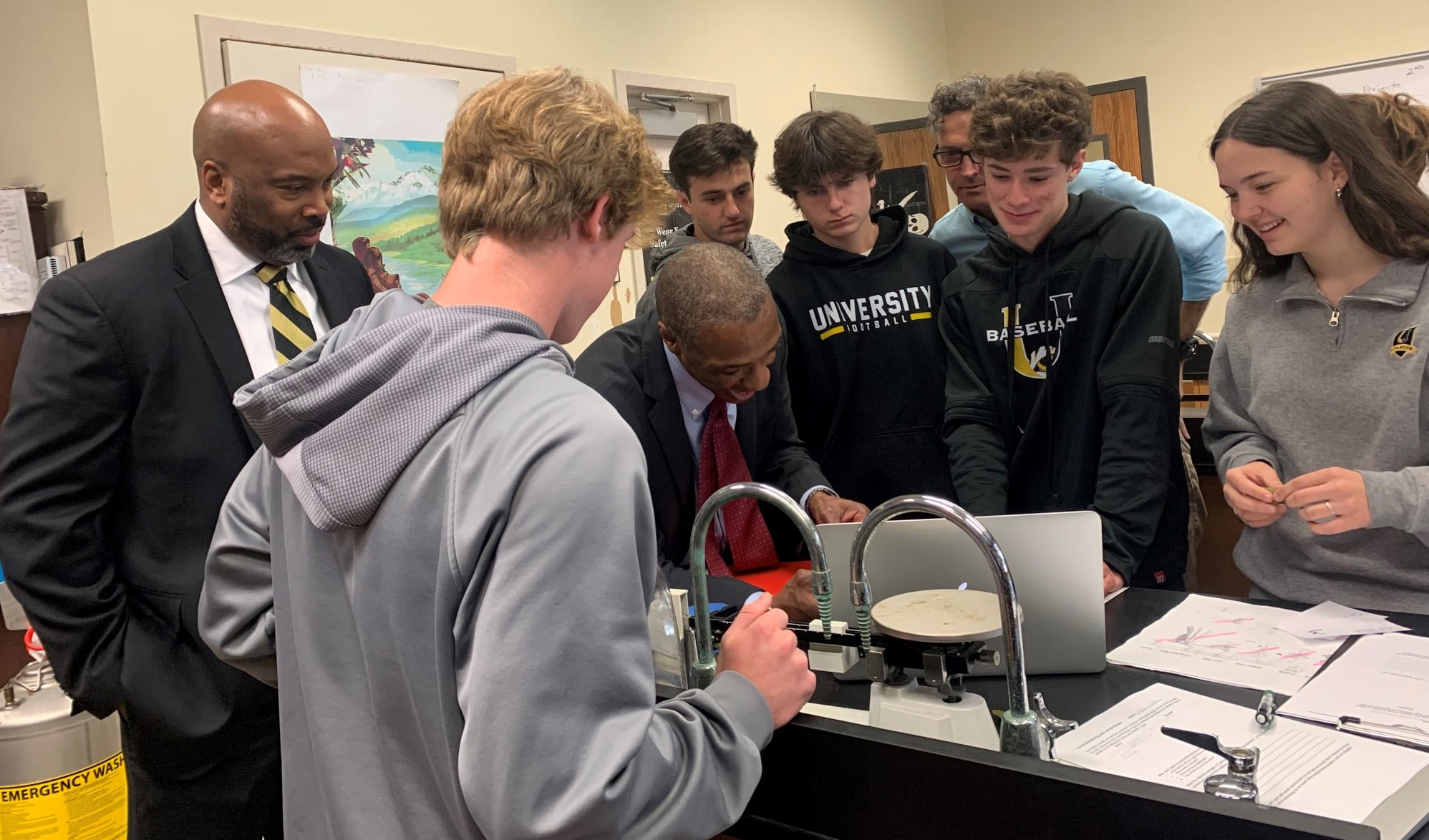 adults interacting with students in science class