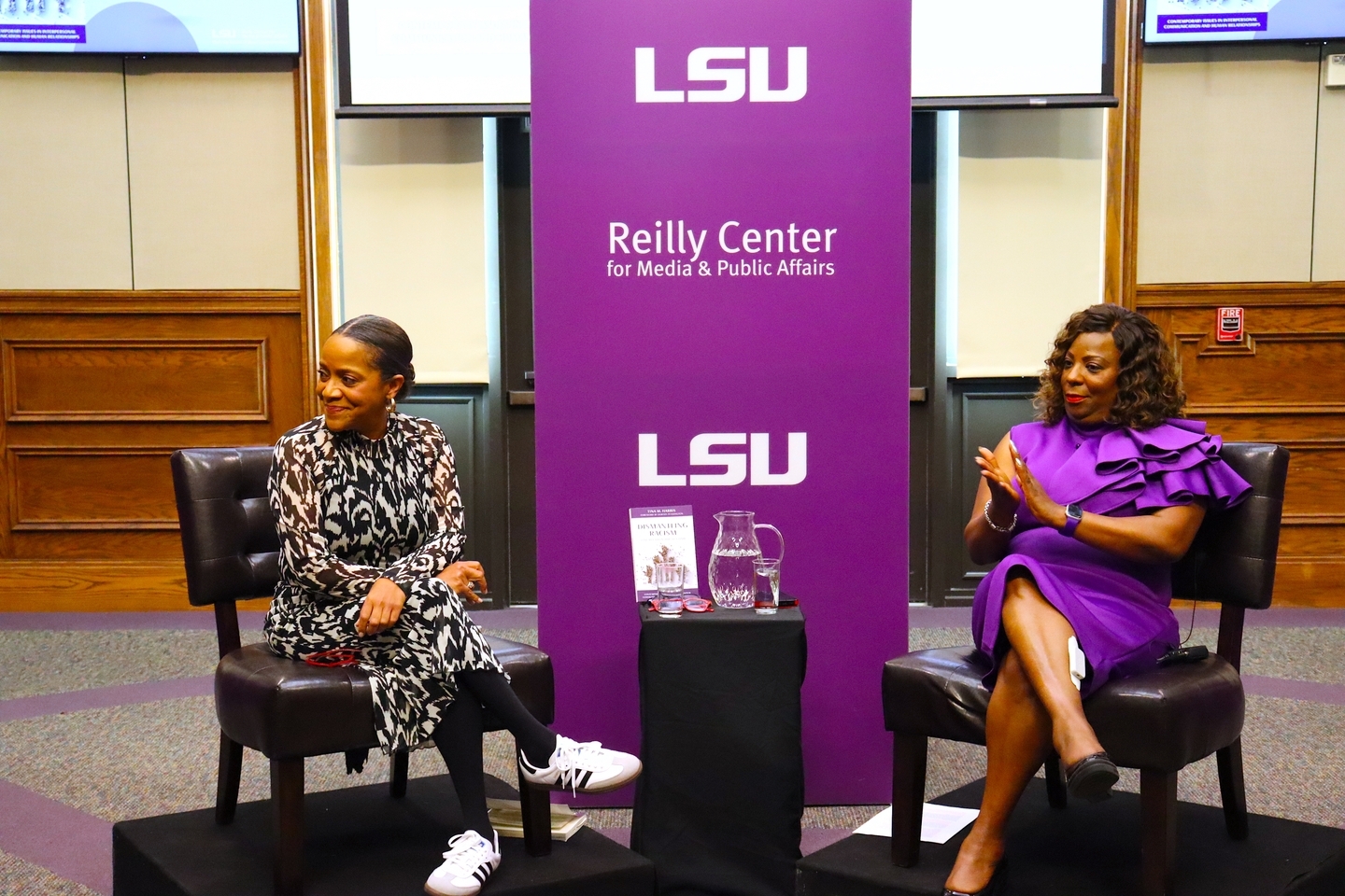 An image of the front of the Holliday Forum with moderator on the left and guest speaker, Tina Harris, on the right sitting in front of a Reilly Center sign.