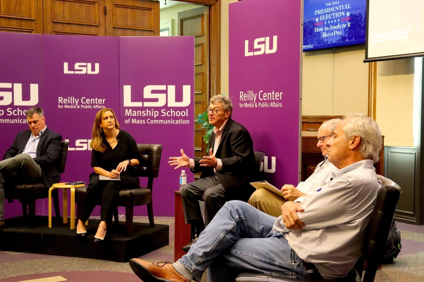 An image of the front of the Holliday Forum with the event panelists and moderator sitting in front of the LSU Reilly Center signs.